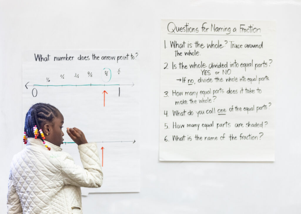 A student writes on the board math calculations