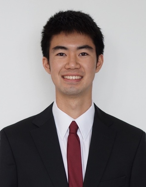 Picture of an Asian man smiling, wearing a black suit and red tie
