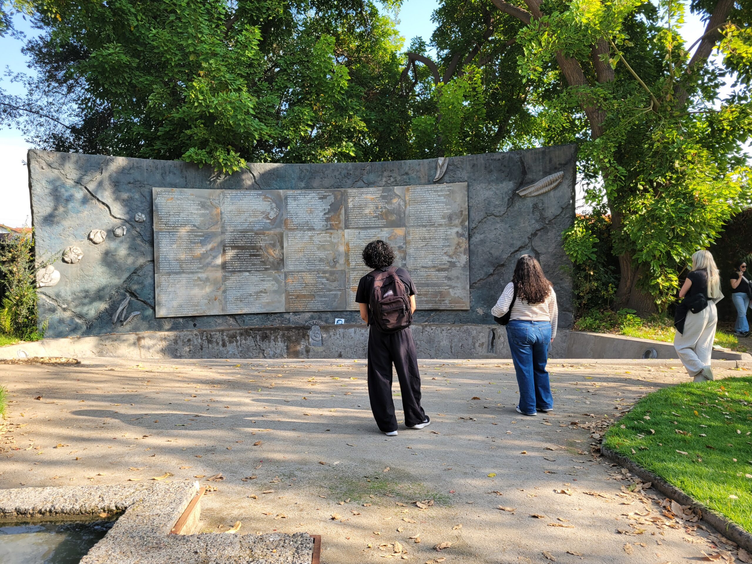 students reflecting in front of a wall of names of those murdered or disappeared at Villa Girmaldi